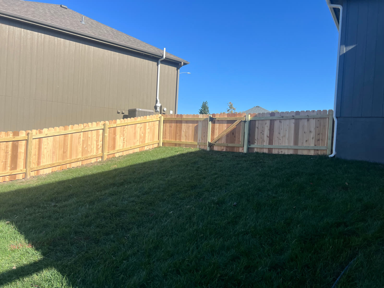 4 ft cedar fence with a Z-brace single gate and black hinges closing the side yard between two homes — Paola, KS
