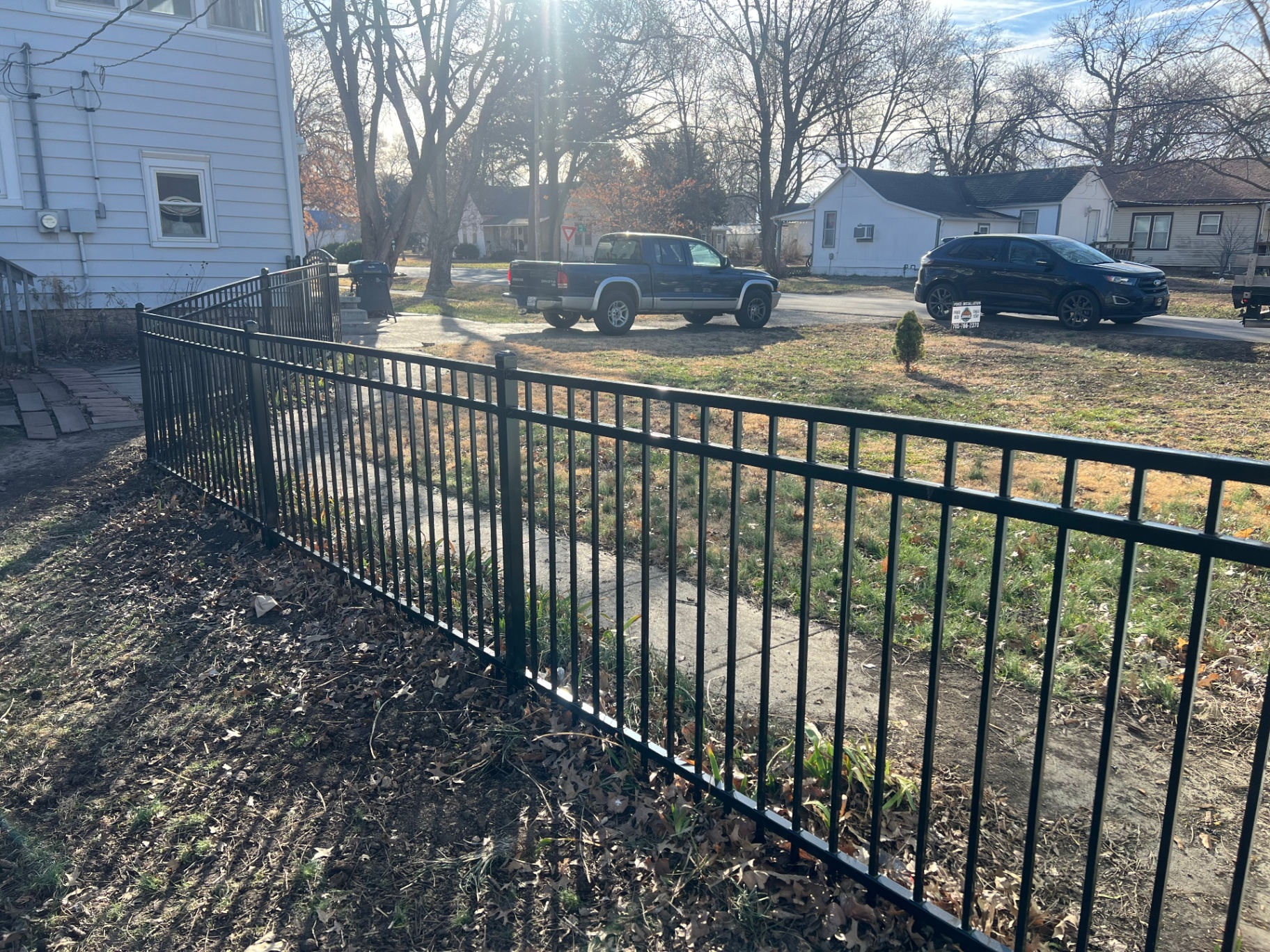 4 ft flat-top black ornamental aluminum fence wrapping a front yard corner at sunset — Overland Park, KS