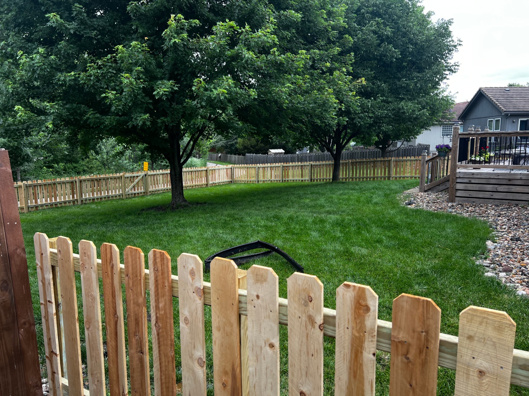 4 ft spaced cedar dog ear picket fence enclosing a Gardner, KS backyard with mature trees