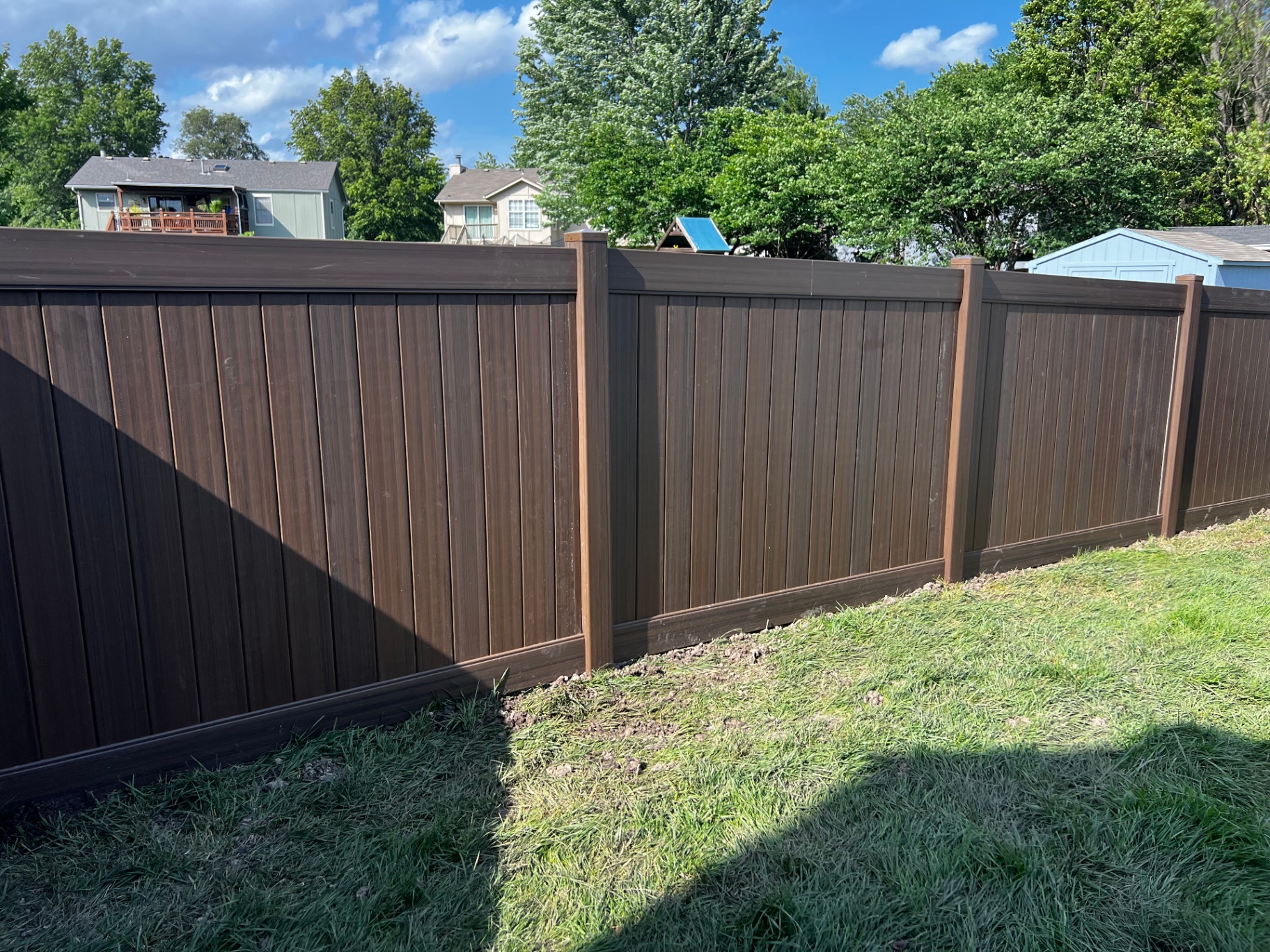 Close-up of 6 ft Woodland Select Chestnut brown vinyl privacy panels with matching posts and post caps — Greenwood, MO