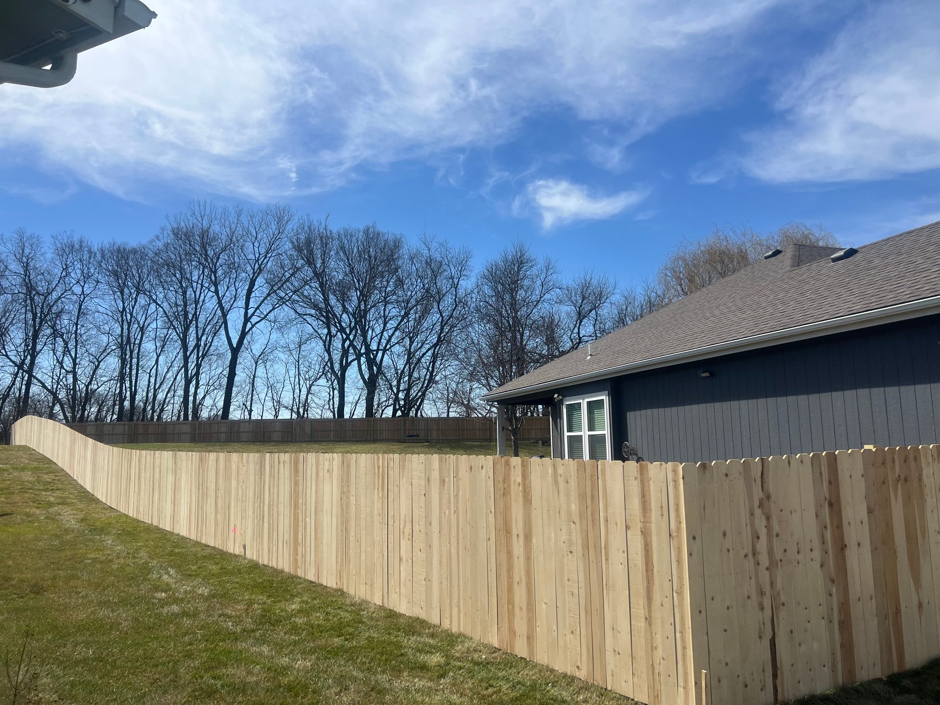 6 ft privacy American cedar fence running along a sloped backyard beside a home in the Kansas City metro