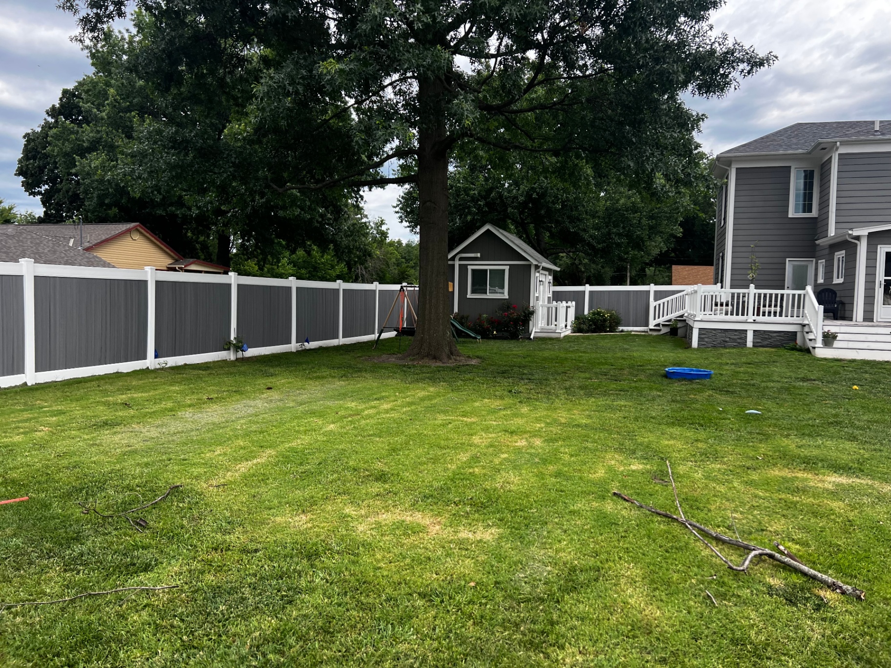 6 ft Woodland Select Gray vinyl privacy fence beside a mature oak and playhouse — Kansas City metro install at quoted vinyl pricing