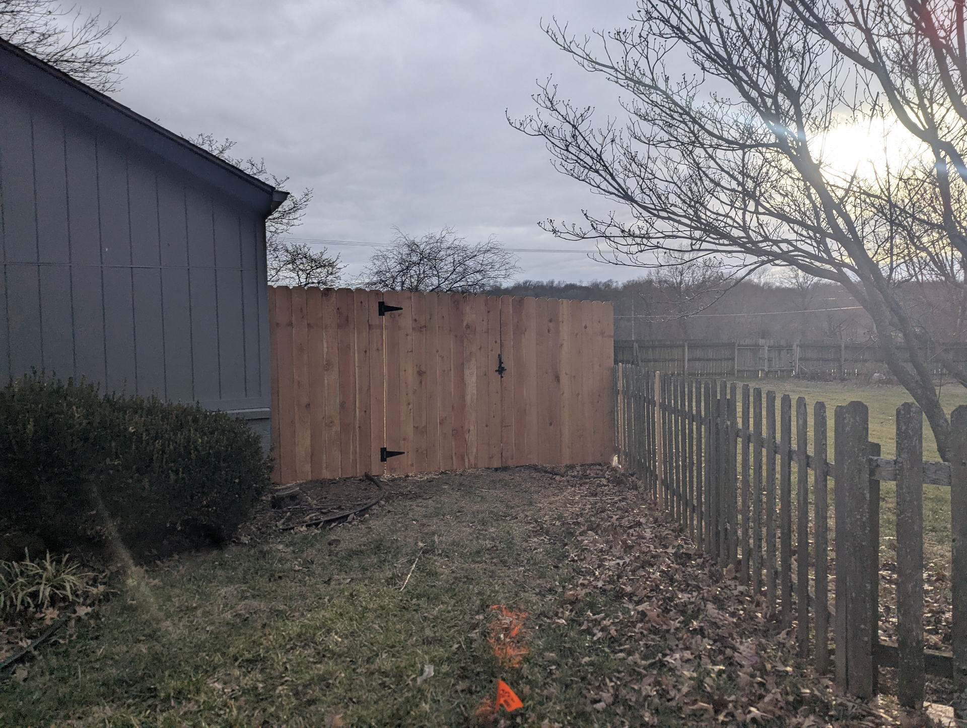 6 ft Western Red Cedar privacy fence with single walk gate and black decorative hardware along the side of a gray home — Shawnee, KS
