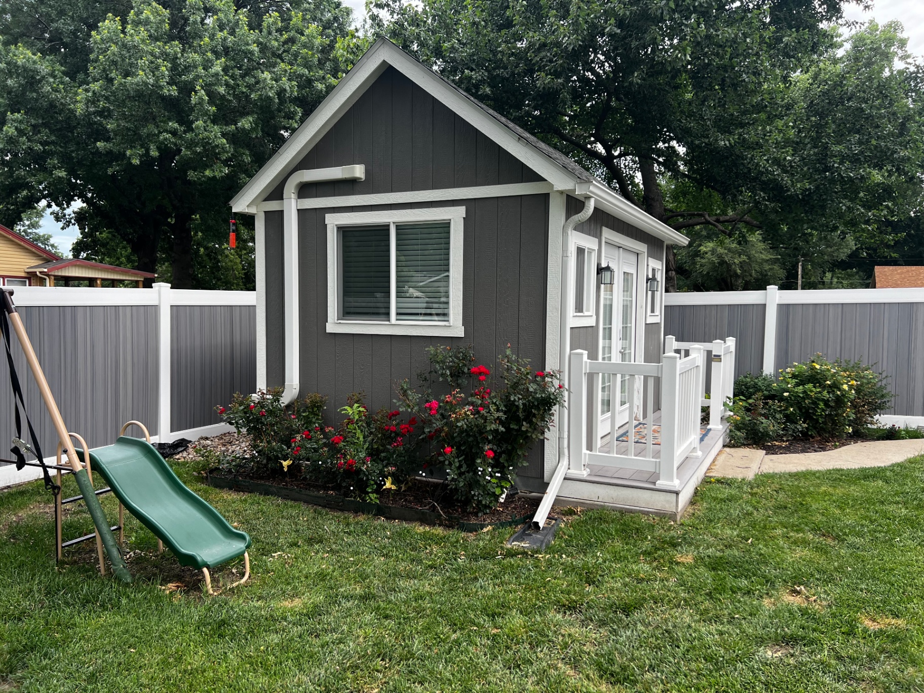 6 ft Woodland Select Gray privacy vinyl fence running along an Independence-area backyard with mature oak and playhouse