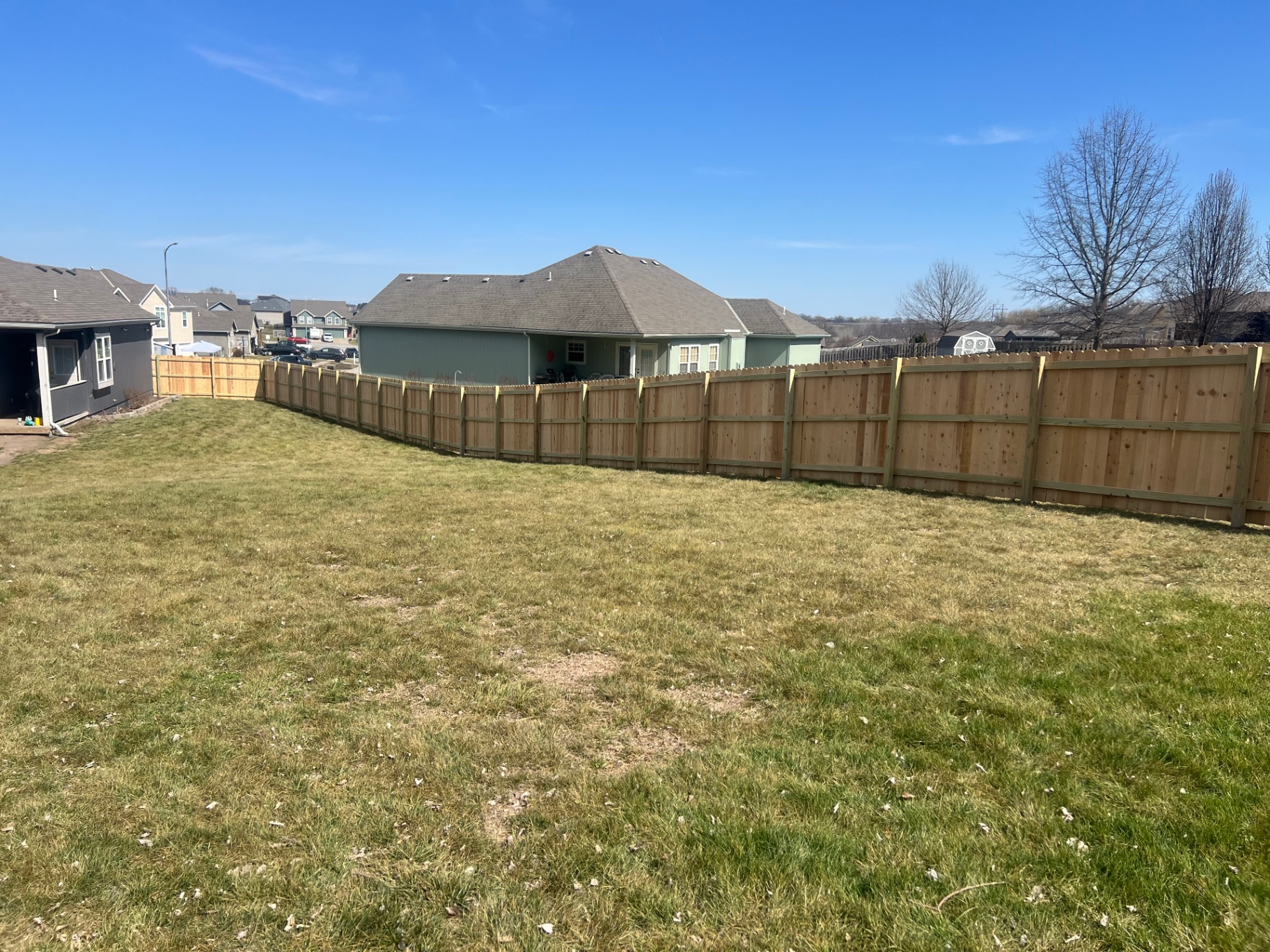 Long diagonal run of 6 ft privacy American cedar fence across a wide KC-metro backyard