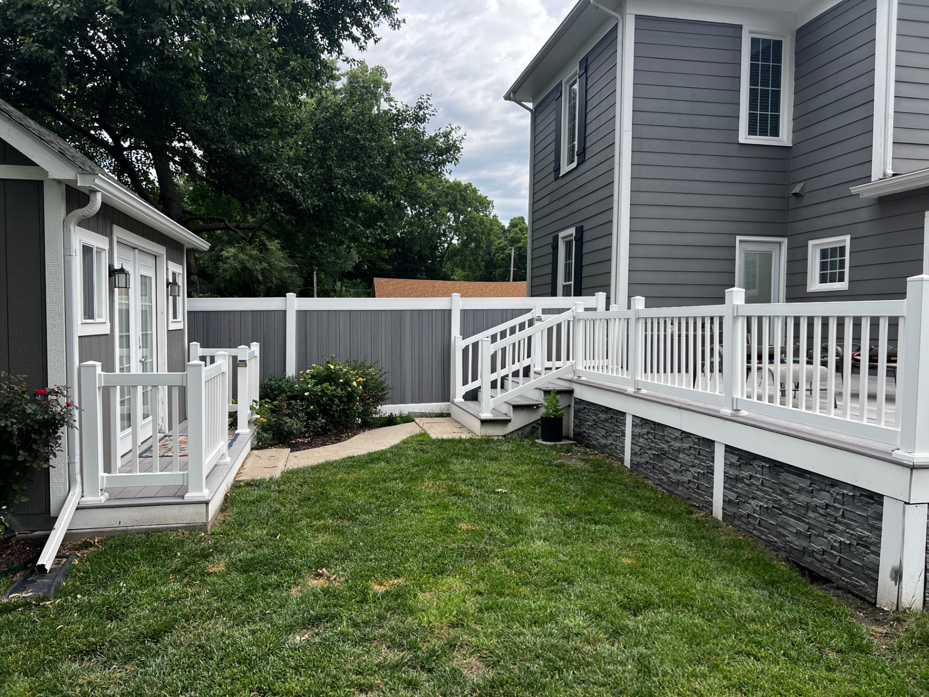 6 ft Woodland Select Gray vinyl privacy fence on a property line beside a deck and two-story home — Kansas City metro