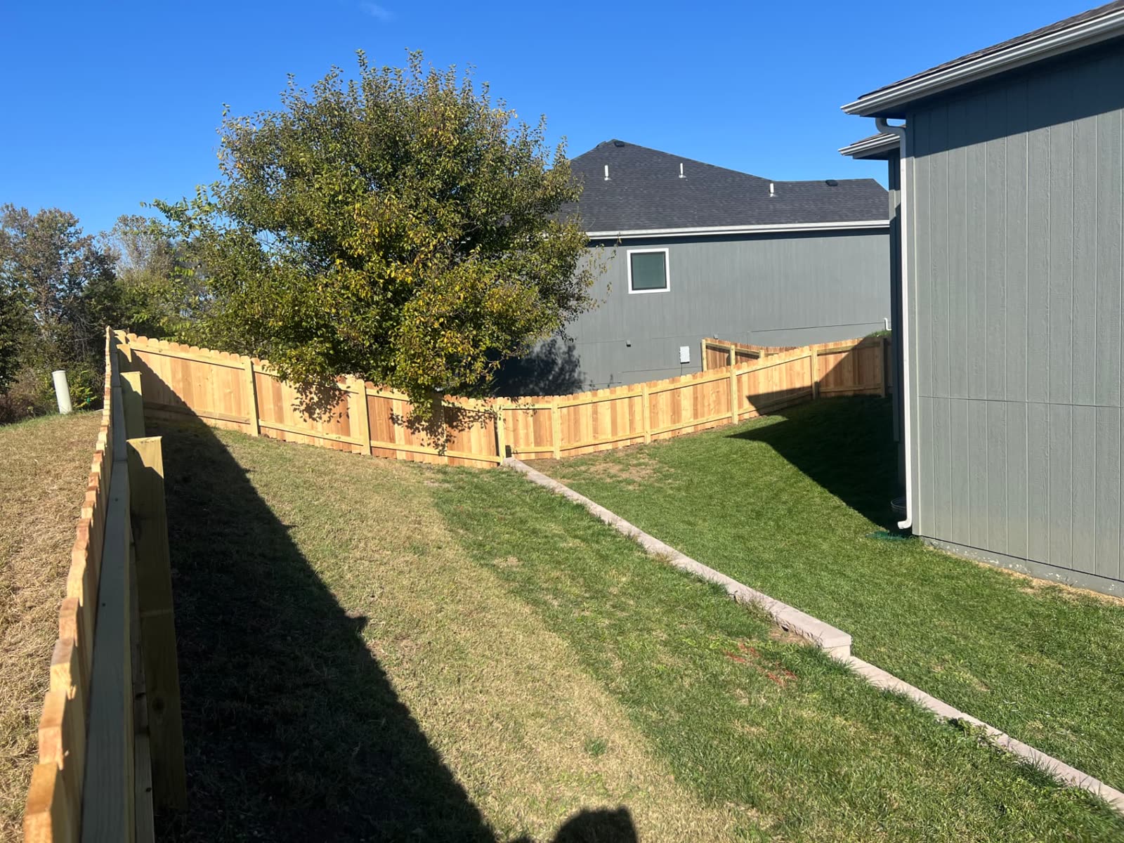 4 ft cedar privacy fence following a sloped backyard between two homes — Paola, KS