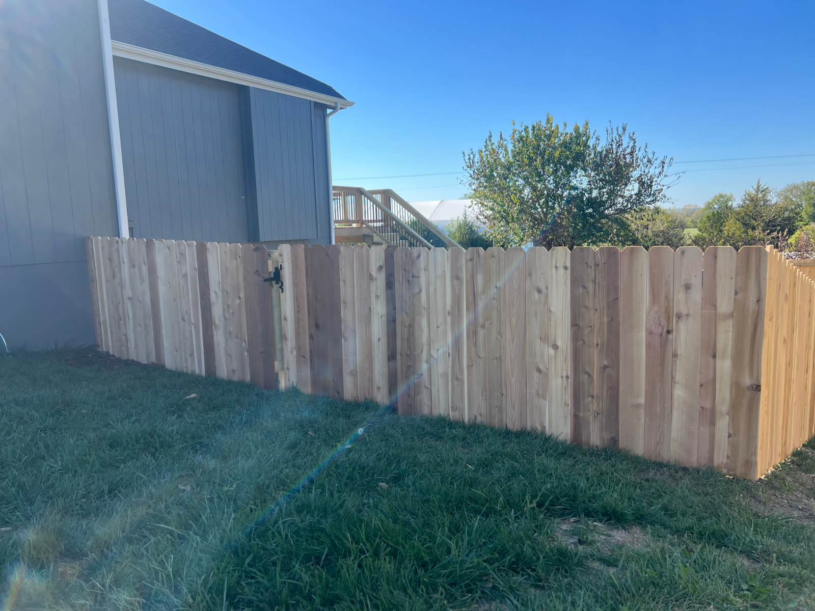 4 ft cedar dog-ear picket fence with a single walk gate and black latch beside a gray house — Paola, KS
