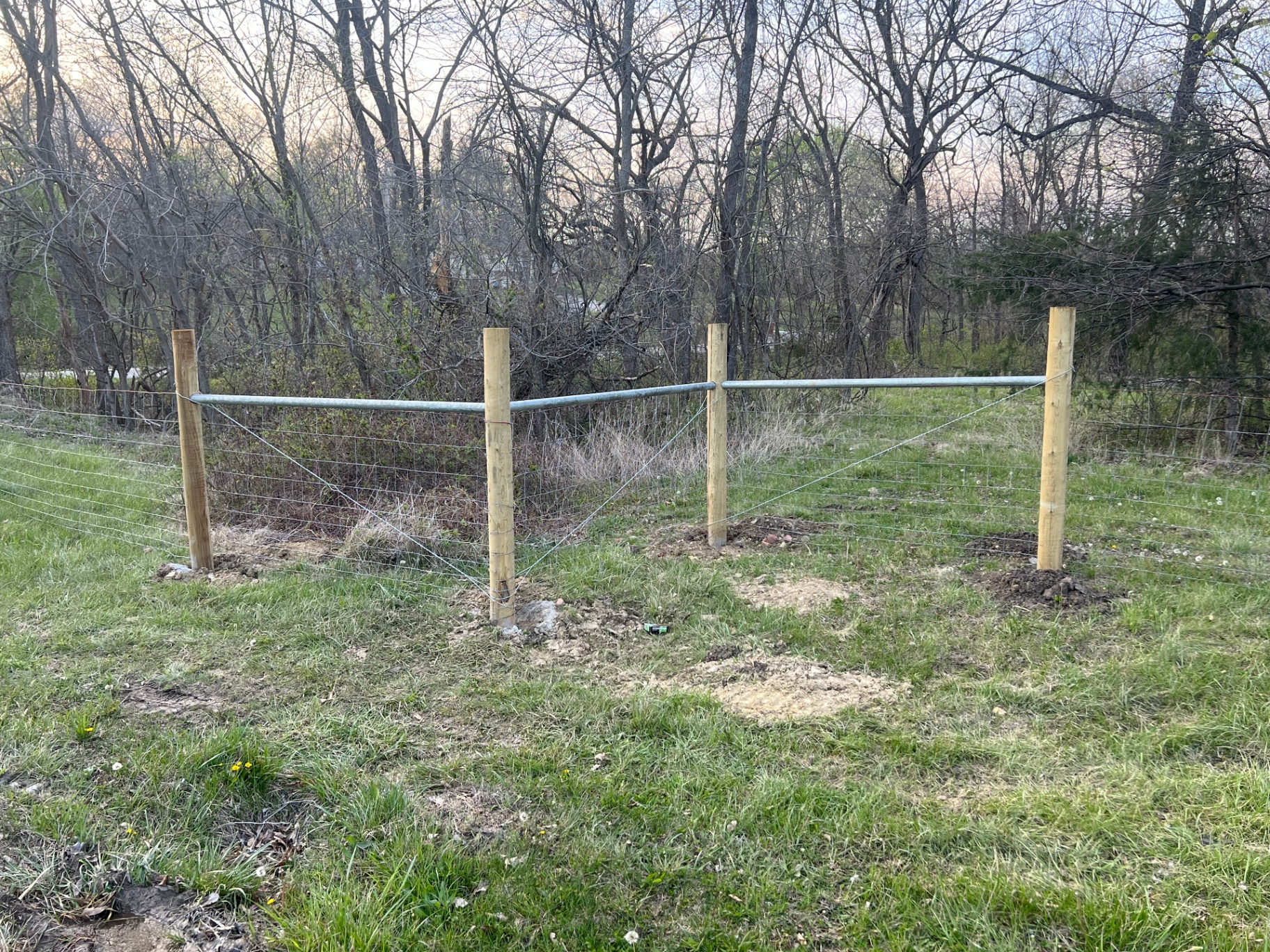 Pressure-treated wood H-brace corner assembly with galvanized top rail and diagonal tension wires securing no-climb welded wire mesh — Spring Hill, KS