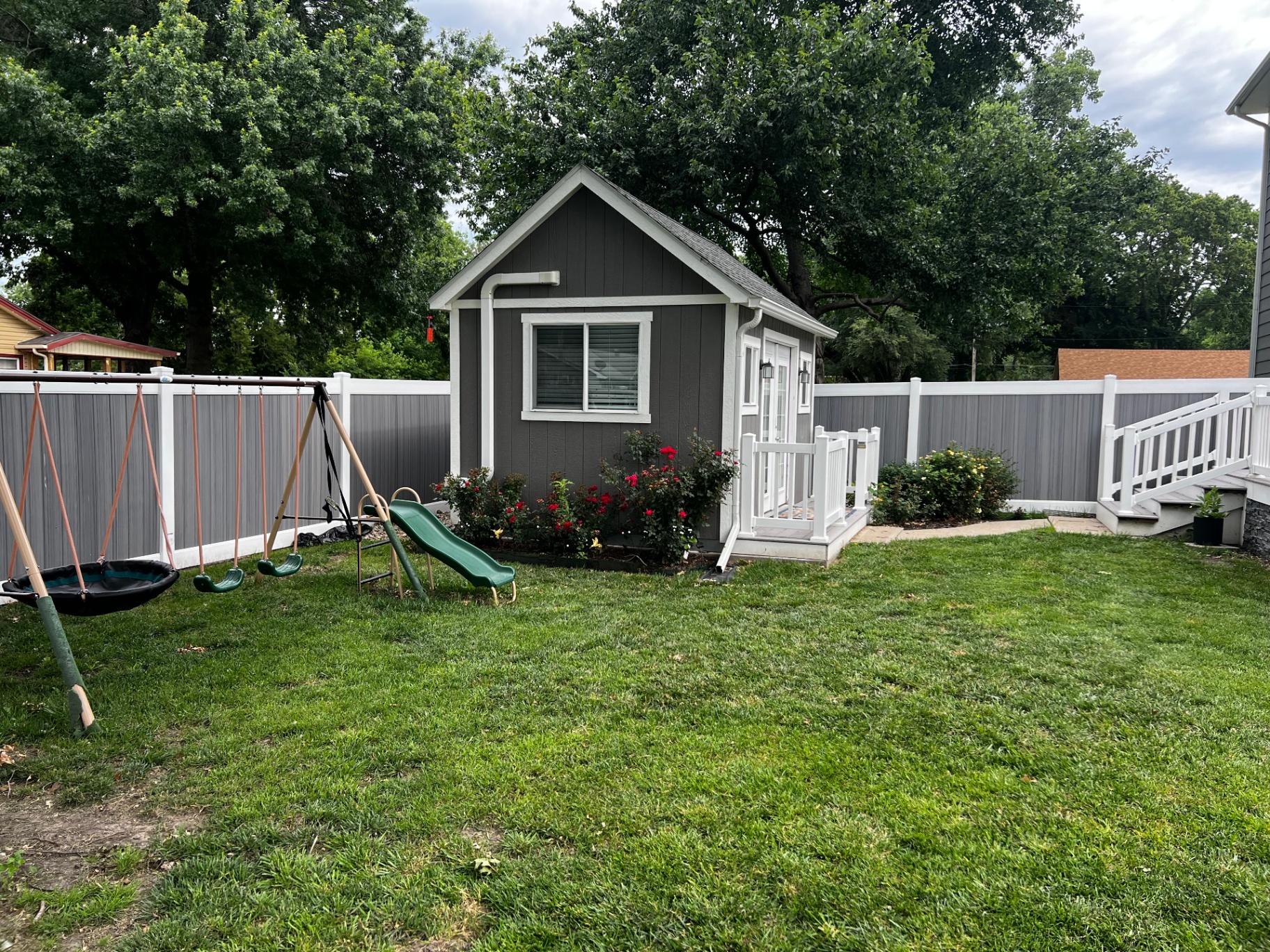 6 ft Woodland Select Gray privacy vinyl fence enclosing a backyard with playhouse and swing set near Independence, MO