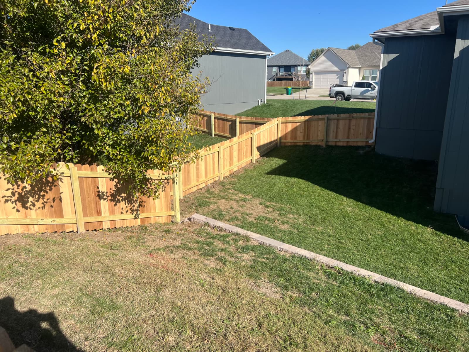 4 ft cedar fence stepping down a side yard toward the street between neighboring homes — Paola, KS