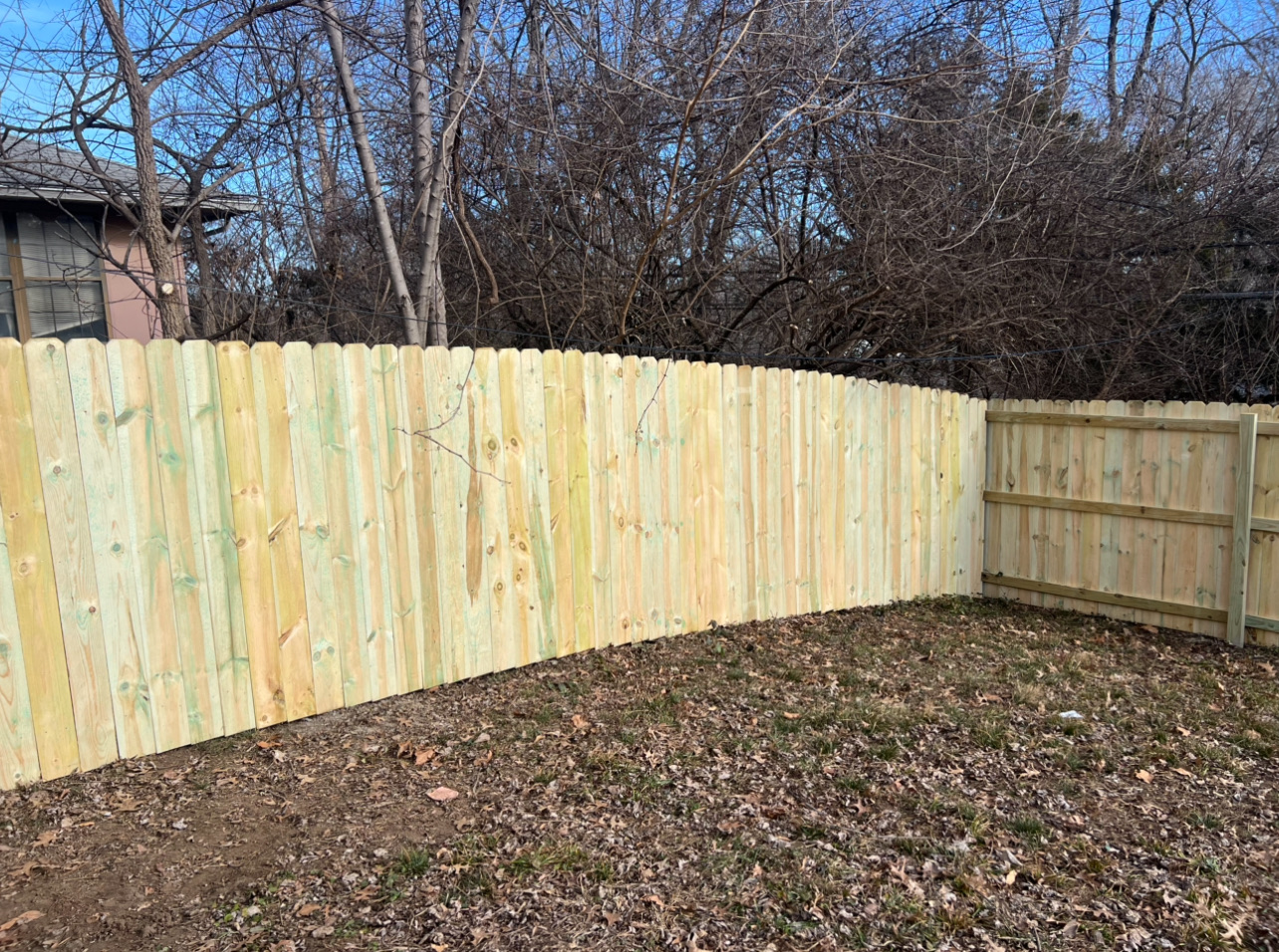 6' privacy pressure treated pine fence enclosing a backyard corner with mature trees