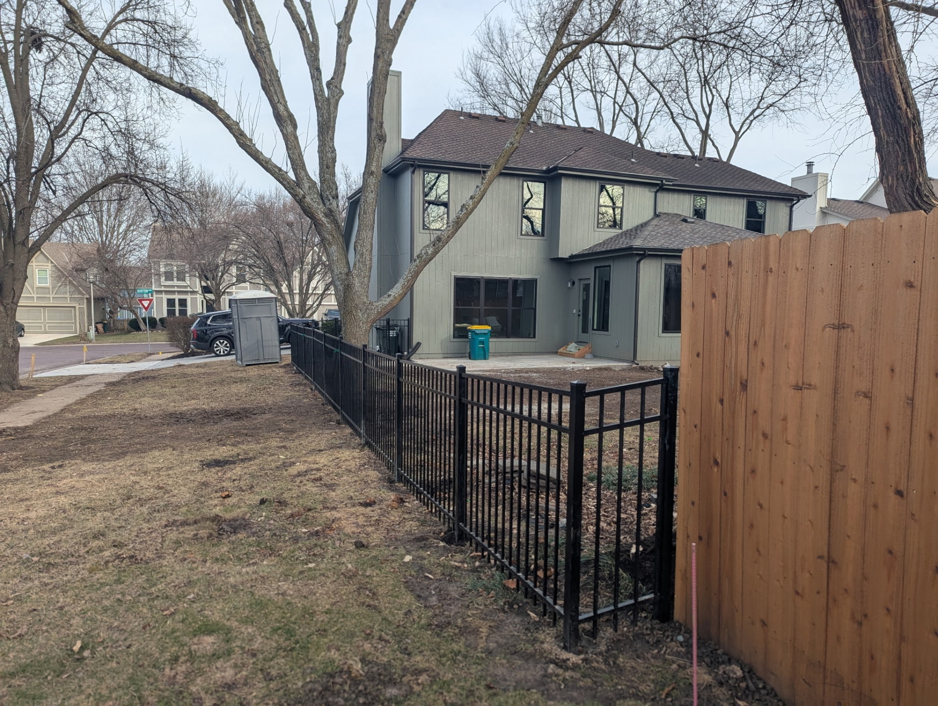 Corner where 4 ft black aluminum fence transitions into an existing wood privacy fence — Overland Park, KS